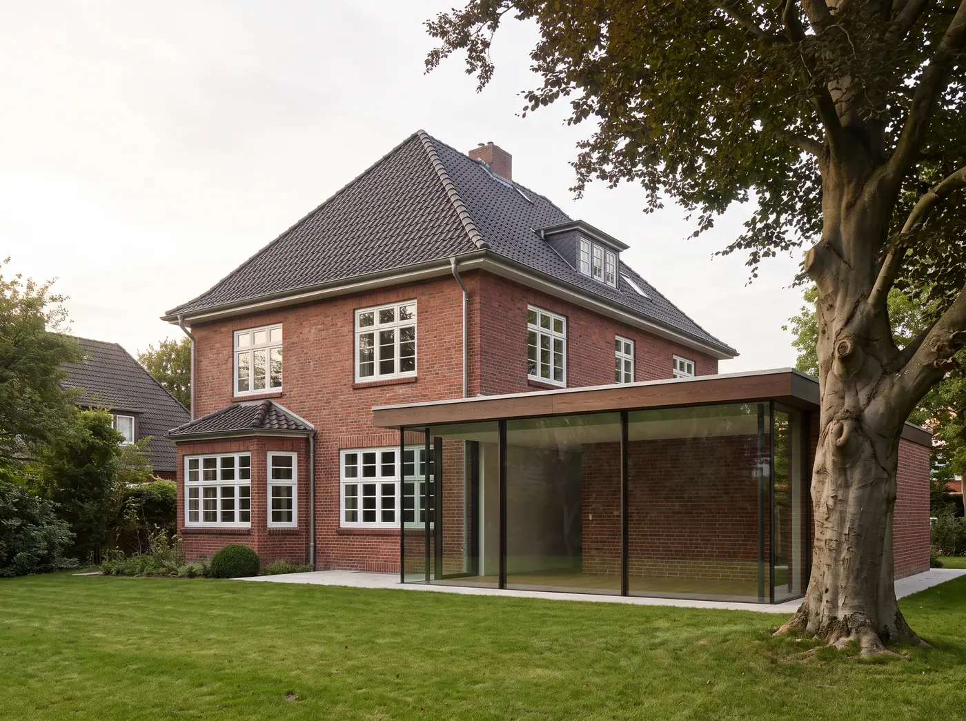 Sanierte Klinkervilla der 1920er Jahre mit neuem gläsernen Anbau zum Garten und alter Blutbuche